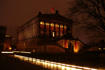 Alte Nationalgalerie bei Nacht auf der Museumsinsel in Berlin. Das historische Bauwerk mit den Säulen und der roten Fassade.