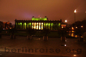 Altes Museum in Berlin auf der Museumsinsel. Die Säulen grün ausgeleuchtet im Hintergrund der Nachthimmel von Berlin und rechts daneben die Nationalgalerie rot ausgeleuchtet.