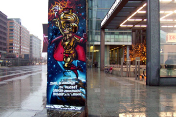 Rest der Berliner Mauer auf dem Potsdamer Platz als Kunstwerk vor dem Eingang zum Bahnhof Potsdamer Platz. Oben auf dem Bild kann man einen Webseitennamen ablesen.